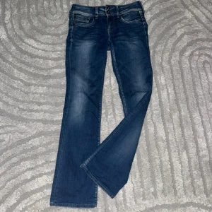 Blå bootcut jeans från Pepe  - Säljer ett par klassiska blå bootcut jeans med snygga detaljer på bakfickorna och dubbla knappar i midjan. Jeansen har normal passform och är perfekta för dig som gillar en tidlös stil. Jag säljer de då de inte passar mig.☺️