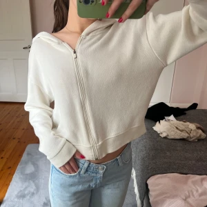 Vit kofta  - En super söt vit lite kroppad kofta med dragkedja och luva. 