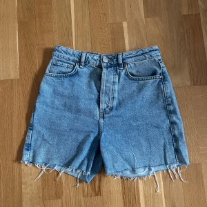 Blå jeansshorts från Bikbok - Säljer ett par klassiska blå jeansshorts från Bikbok. Modellen är högmidjad med fem fickor och gylf med knapp. Perfekta till sommaren💕