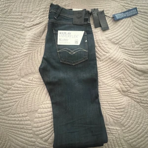 Replay Hyperflex jeans  - Säljer ett par Replay Hyperflex jeans i mörkblå tvätt med klassisk femficksdesign och snygga kontrastsömmar. Jeansen har normal passform och är tillverkade i stretchigt material för extra komfort. Märkeslapp bak i midjan och tydlig Replay-logga.