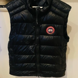 Svart väst från Canada Goose - Säljer en svart väst från Canada Goose, den har lite skavanker på magen men det är snabblagat