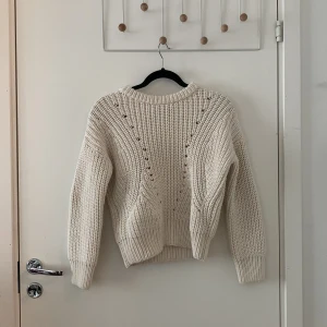 Vit stickad tröja från & Other Stories - Säljer en chunky vit stickad tröja från & Other Stories. Tröjan har lång ärm, rund halsringning och dekorativa hålstickade detaljer framtill. Perfekt för lager-på-lager och enkel att styla till olika outfits.