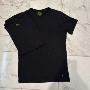 Svart t-shirt från Polo Ralph Lauren - Två svarta t-shirts från Polo Ralph Lauren med klassisk passform och rund hals. T-shirten har en liten röd broderad logga nertill på framsidan. Perfekt basplagg till garderoben. 100kr/st💯