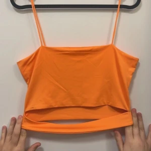 Orange croppad linnetopp - Säljer en snygg orange croppad linnetopp med tunna axelband. Med en utklippt detalj! Perfekt för varma dagar och enkel att matcha med jeans eller kjol.