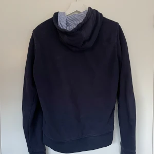 Mörkblå hoodie med dragkedja från Moncler - Säljer en mörkblå hoodie från Moncler med dragkedja framtill och huva. Personligen tycker jag att den är snyggare utan snören. Snören fins. Skickar med brevid. Priset är inte hugget i Sten.  