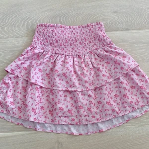 Rosa blommig volangkjol från Gina Tricot - En jättefin, stretchig och kort kjol från Gina tricot Young i storlek 158/164 som även passar xs. Den har inga defekter och sitter väldigt fint. Hör gärna av er vid frågor!