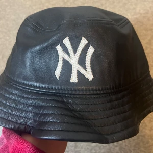 Bucket hat New Era - Säljer en svart bucket hat i 100% Genuine leather från New Era med New York Yankees-logga framtill och New Era-logga på sidan. 🤍🖤