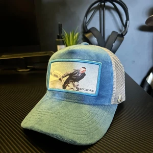 Blå/vit maggiore keps - Snygg keps i blått och beige med mesh-bakstycke och böjd skärm. Framtill finns ett tryckt motiv med en person och texten 'MAGGIORE'. Perfekt accessoar för en avslappnad stil och till sommaren. Nypris 800 använd en gång box och bag medföljer 