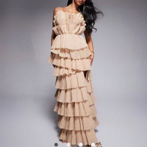 Beige volangklänning asos - Säljer en maxilång beige klänning med flera plisserade volanglager. Klänningen har en luftig och elegant siluett, perfekt för speciella tillfällen. Ger en riktigt lyxig känsla och sticker ut med sin unika design. Den är kemtvättad