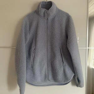 Ljusblå fleecejacka  - Mysig ljusblå fleecejacka med hög krage och hel dragkedja framtill. 