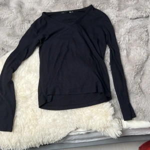 Svart ribbad långärmad tröja från 157 - Svart långärmad tröja från 157 i ribbat material. Tröjan har v-ringning och är figurnära i modellen. Perfekt basplagg till garderoben och enkel att matcha med olika outfits.