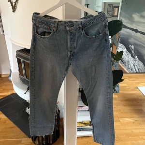 Levis 501 ljusblå jeans - Klassiska Levis 501 jeans i ljusblå tvätt med raka ben och femficksmodell. Jeansen har knappgylf och normal passform. Perfekta för en avslappnad stil och ikonisk denim-look.