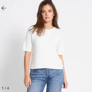 Vit kortärmad kofta med knappar - Säljer en söt vit kofta med korta ärmar och knäppning framtill. Perfekt till jeans eller kjol för en enkel och fräsch look. Mjuk och skön, passar till många tillfällen.