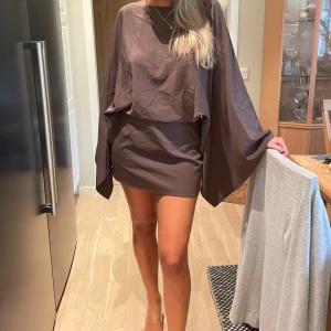 Brun kortklänning med öppen rygg - Säljer en brun kortklänning med vida ärmar och öppen rygg.  Slutsåld på hemsidan.