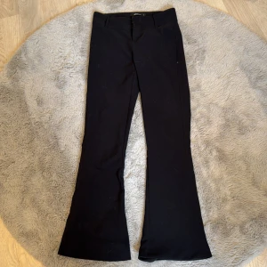 Svarta bootcut-byxor Gina Tricot S - Svarta bootcut-byxor från Gina Tricot i storlek S. Byxorna har två knappar och dragkedja framtill samt hällor för bälte. Snyggt utsvängda ben och klassisk look som passar till många olika stilar.