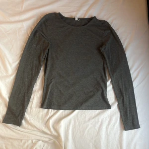 Mörkgrå långärmad tröja från Nelly - En basic mörkgrå långärmad tröja från Nelly i storlek M. Tröjan har rund halsringning och är tillverkad i mjuk bomullsmix, perfekt för lager-på-lager eller som den är. Enkel och stilren modell som funkar till det mesta. Nypris 199 kr.