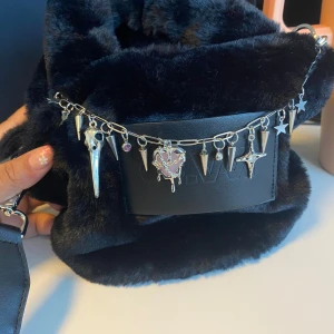 Handgjord nyckelring/ kedja/ bagcharm - Smycket har en silverfärgad kedja med spikes, stjärnor och unika hängen som ger en edgy vibe. Perfekt för dig som vill sticka ut med accessoarer som syns. Tyvärr har den blivit liggandes då jag inte använt den, så säljer nu vidare. Köpte denna och två andra (säljer dessa också) på loppmarknad av en tjej som ställde ut egengjorda nyckelringar. Material är jag osäker på, någon typ av stål/metall skulle jag gissa på, förutom det rosa i berlocken som är plast. Nypris 300kr, kan tänkas gå ned i pris!