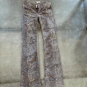 Leopardmönstrade bootcut jeans från Nelly - Snygga bootcut jeans från Nelly med leopardmönster i bruna och beige toner. Byxorna har klassisk femficksdesign, knappgylf och normal passform. Perfekta för dig som vill sticka ut med ett djurmönstrat statement.