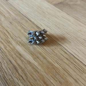 Silvrig ring med nitar från Edblad - Cool och chunky ring i silverfärgad metall från Edblad, täckt med små konformade nitar som ger en edgy vibe. Bred design som verkligen sticker ut och passar perfekt för dig som gillar statement-smycken.