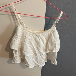 Vit Volangtopp från Abercrombie & Fitch i storlek XS - En volangtopp med justberbara axelband som passar storlek XS/S. Lite skrynklig men går lätt att stryka