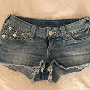 Blå lowwaistjeans jeansshorts från True Religion - Snygga blå jeansshorts från True Religion med fransiga kanter. Dom är lowwaist och är i storlek 25🫶🏻 skriv om ni har frågor!💕