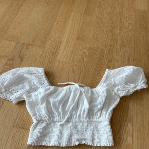 Vit topp  - Söt sommrig vit blus från New yorker i storlek XS. Toppen har puffiga korta ärmar, broderade detaljer och smockad midja. Du kan välja om du vill ha den of shoulder eller inte. Använd få gånger 