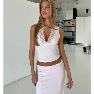 Ljusrosa spetsdetaljerad linnetopp - Topp från Venderbys, helt oanvänd med prislapp kvar. Supersöt ljusrosa linnetopp med djup v-ringning och bred spetskant framtill. Toppen är ärmlös och har en figurnära passform som framhäver siluetten. Perfekt för dig som gillar romantiska och feminina vibes.