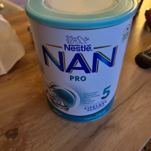 NAN PRO 5 - Detta är inte en bok, utan en burk med Nestlé NAN PRO 5, ett näringspulver för barn. Produkten är framtagen för att ge långvarig näring och innehåller vitaminer och mineraler. Perfekt för dig som vill ge ditt barn en bra start.