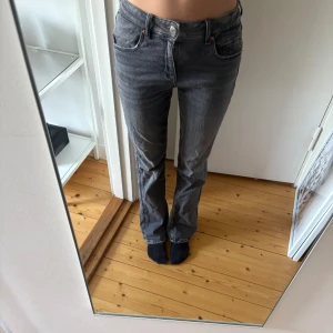Grå/svarta bootcut jeans - Säljer ett par grå/svarta jeans med bootcut passform och låg midja. Jeansen har klassiska fem fickor, silverfärgad knapp och dragkedja. Tillverkade i mjukt denimtyg som ger en avslappnad vibe. Perfekta för dig som gillar en tidlös look med lite edge. Storlek 152💓