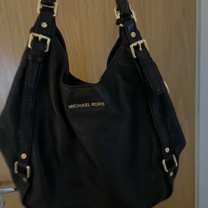 MK väska - Jätte fin Michael kors väska med guld detaljer, äkta läder och äkta väska. Org pris 4400kr, Perfekt för skolan då mycket saker får plats i den och bara allmänt snygg för annat oxå!