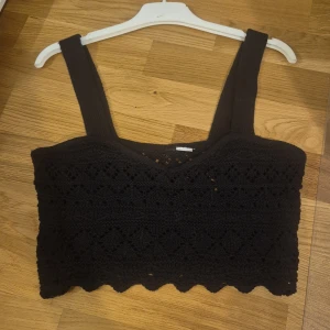 Svart virkad croppad linnetopp - Svart croppad linnetopp med breda axelband och virkat mönster. 🌸Toppen har en snygg v-ringning och vågig kant nertill.🌸 Perfekt för sommaren och ger en chill boho-vibe till din outfit🫶. Fångar upp allas uppmärksamhet💐💐💐😊 priset kan diskuteras♡