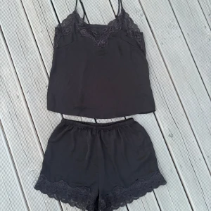 Pyjamasset med spets  - Säljer ett svart pyjamasset från H&M med linne och shorts, pyjamaslinnet har spetsdetaljer upp till och shortsen har spetsdetaljer vid benslutet. Pyjamasen är i ett lätt och luftigt material. (Har klippt bort lappen i toppen och shortsen). 