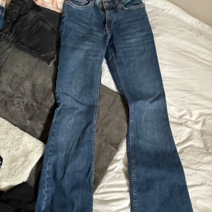 Gina blå bootcut jeans - Klassiska  jeans i blå denim med bootcut passform. Snyggt slitna detaljer och femficksmodell. Perfekta för dig som gillar en tidlös look med lite vidare ben. Ikonisk läderpatch bak i midjan och robust bomullsmaterial. Midwaist/lowwaist skulle jag säga. Utsvängda