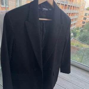 Svart kavaj från Zara - Stilren svart kavaj från Zara i oversized passform, raka axlar, fickor med lock och är helfodrad. Väldigt fint skick - storlek S