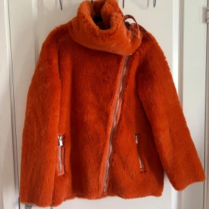 Orange teddyjacka Icona Pop x Gina Tricot - Säljer en orange teddyjacka från Icona Pop x Gina Tricot. Jackan har oversized krage, sned dragkedja, två fickor med dragkedja och coola spänndetaljer vid halsen. Mjuk och fluffig känsla, perfekt för att sticka ut i höst och vinter.