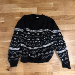 Svart stickad tröja med mönster Lindex - Svart stickad tröja från Lindex med grått och vitt nordiskt mönster över bröstet och ärmarna. 