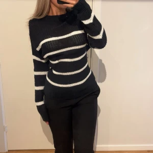 Stickad tröja - Snygg svart stickad tröja med vita ränder. Tröjan har aldrig använts!
