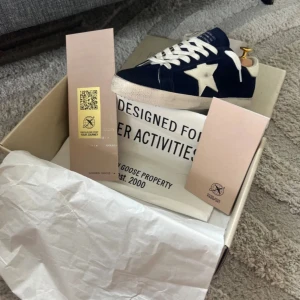 Blå Golden Goose sneakers med stjärna - Snygga sneakers från Golden Goose i mörkblå mocka med vit stjärndetalj på sidan och vit hälkappa. Skorna har vita snören och platt sula. Perfekta för dig som gillar en cool och avslappnad stil med premiumkänsla.