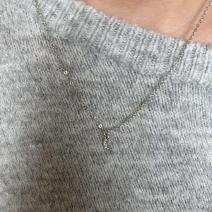 Silverhalsband med månberlock - Ett tunt silverfärgat halsband med en liten måne som hänge. Månberlocken är dekorerad med små glittrande stenar som ger ett subtilt bling. Perfekt för dig som gillar minimalistiska smycken med en touch av magi. Säljer pga att den inte kommer till användning. Nytt skick!