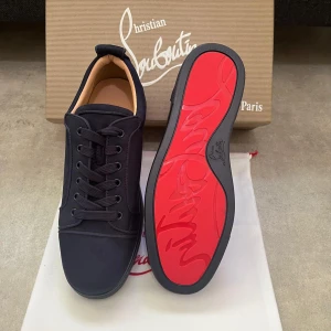 Marinblåa sneakers från Christian Louboutin - Helt nya snygga blåa sneakers från Christian Louboutin med klassisk röd sula och diskret logga. Skorna har rund tå, snörning och är tillverkade i ett lyxigt material med beige innersula. Perfekta för dig som vill sticka ut med exklusiv stil.