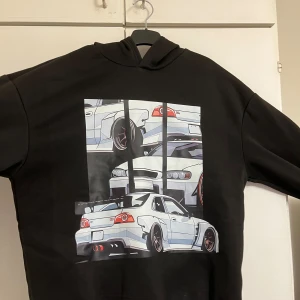 Svart hoodie med biltryck från SHEIN - Svart hoodie från SHEIN med stort tryck av tecknade sportbilar på framsidan. Tröjan har huva, lång ärm och är gjord i mjukt fleecematerial på insidan. Perfekt för dig som gillar streetstyle och bilar.