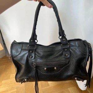 Svart axelväska i skinn med detaljer - Supersnygg svart väska som tyvärr inte kommer till användning för mig💕  Snygga detaljer och en ficka utanpå och en inuti! Den kommer även med ett längre axelband.   Skriv vid intresse/frågor/mått eller något annat du undrar!