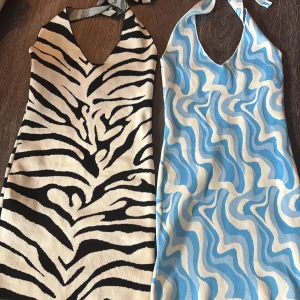 Två stickade halterneckklänningar Gina Tricot - Säljer två kortklänningar från Gina Tricot i storlek S. Ena är svartvit med zebramönster och den andra är blåvit med vågigt mönster. Båda har halterneck med knyt i nacken och v-ringad hals. 