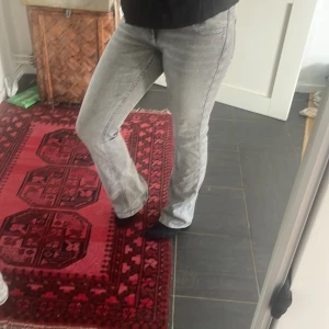Grå bootcut jeans med broderade fickor - Säljer ett par grå jeans med bootcut passform och snygga broderade detaljer på bakfickorna. Jeansen har normal midja och klassisk femficksdesign. Perfekta för dig som gillar en avslappnad men ändå trendig look.