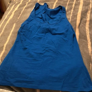 Blå linnetopp från Amisu - Snygg blå linnetopp från Amisu i enkel och klassisk modell. Toppen är ärmlös med rundad halsringning och tillverkad i mjuk bomull, perfekt för varma dagar eller lager på lager. Färgen är klarblå och toppen har en clean look utan mönster eller detaljer.