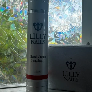 Lilly Nails Hand Cream Strawberry 120ml - Oanvänd Handkräm från Lilly Nails med doft av jordgubb i en vit och silverfärgad pumpflaska på 120 ml. Innehåller bland annat avokadoolja och panthenol för mjuka och lena händer. Snygg och stilren design, perfekt att ha i väskan eller på skrivbordet.