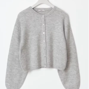 Grå stickad kofta med knappar - Mysig grå stickad kofta från gina tricot med rund halsringning och knäppning framtill. Koftan har långa ärmar och en lite croppad passform som ger en trendig look. Perfekt att slänga över en t-shirt eller linne.