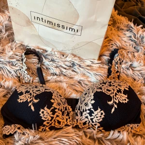 Marinblå spetsblus från Intimissimi - Helt ny supersnygg marinblå blus från Intimissimi med beige spetsdetaljer i blommigt mönster. Axelbanden är dekorerade med samma spets och ger en lyxig känsla. Perfekt för dig som vill ha något extra till outfiten. 