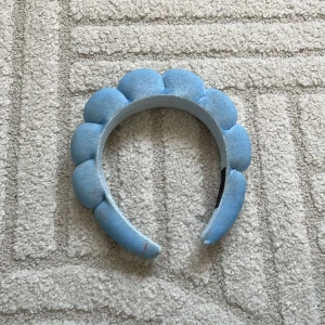Blått puffigt diadem i sammet - Superfint diadem i ljusblå sammet med puffad design som ger en cool och trendig look. Perfekt accessoar för att lyfta vilken outfit som helst med en touch av färg och volym.