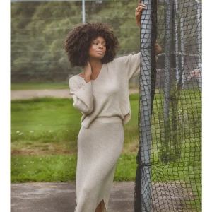 Beige stickad tröja med v-ringning med lång kjolfrån Isay - Säljer en beige stickad tröja med tillhörande lång kjol från Isay med snygg v-ringning och diskret strukturmönster. Tröjan har långa ärmar och är tillverkad i en mjuk mix av bomull och viskos. Perfekt för dig som gillar en clean och chill stil. Aldrig använd.